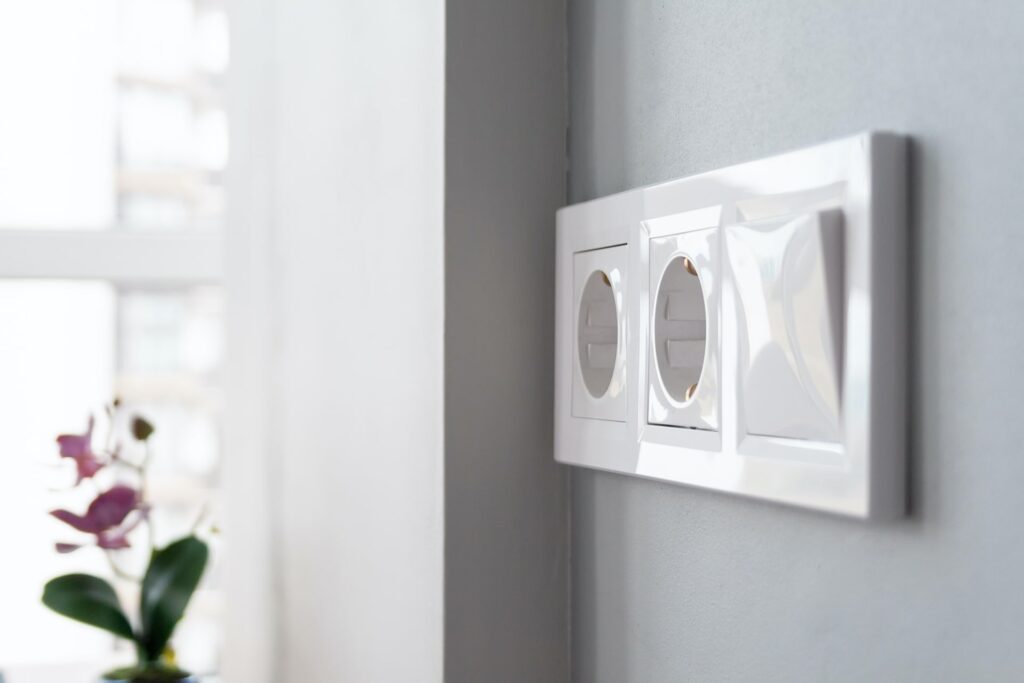 One Thing You Need To Know About The Bath Outlet Location - River City Boston A white wall-mounted electrical outlet featuring two sockets, ideal for contemporary bathroom designs by River City Construction Inc.