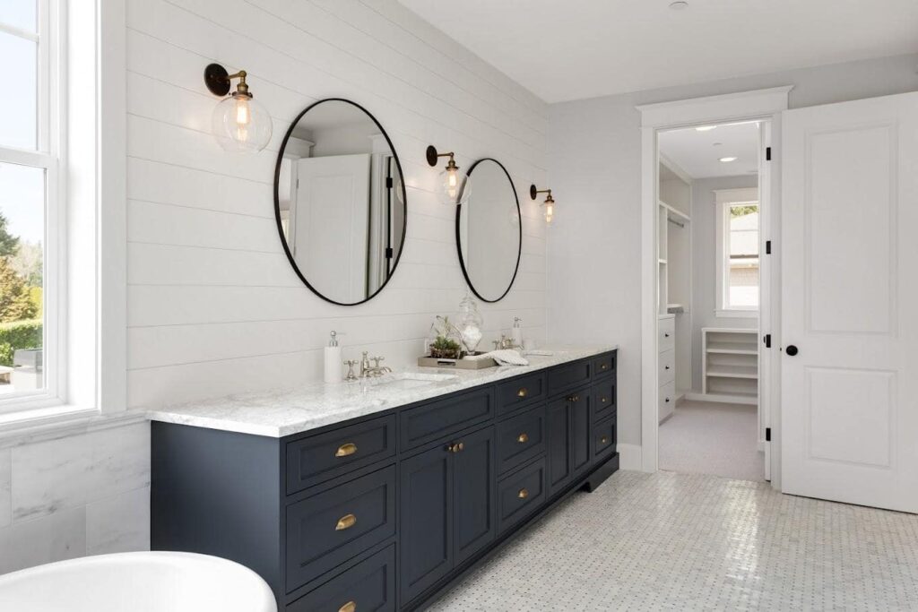 Bathroom Remodeling - River City Construction A stylish bathroom featuring white cabinets and elegant black marble countertops, designed by Medford bathroom remodeling experts.